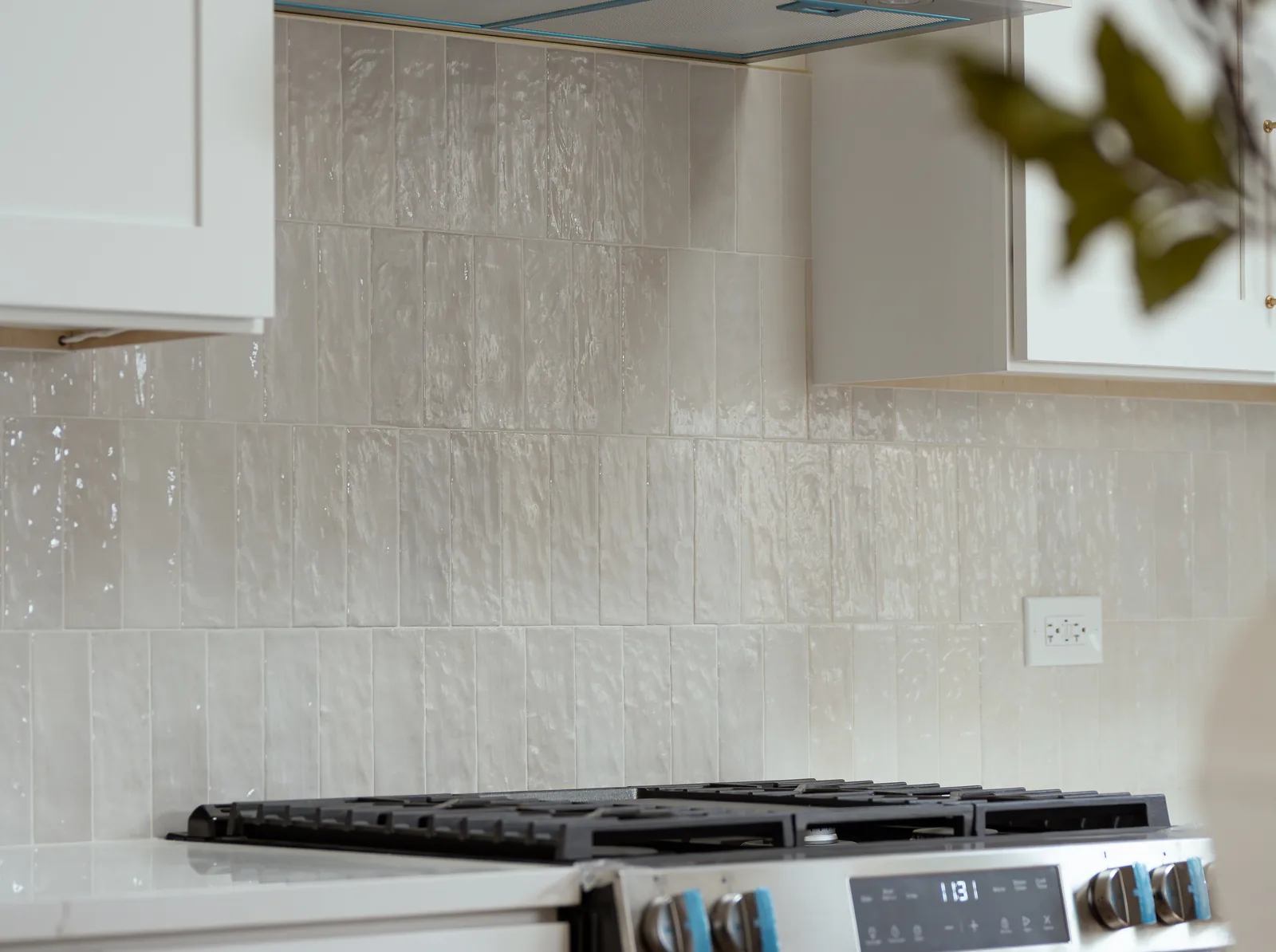 Completed kitchen stovetop with custom cabinetry and a tiled backsplash